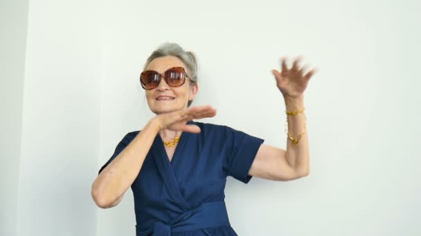 Retrato femenino de la hermosa abuela de edad con el pelo gris y la cara con arrugas está bailando sobre fondo blanco, día de las madres, feliz jubilación — Vídeos de Stock