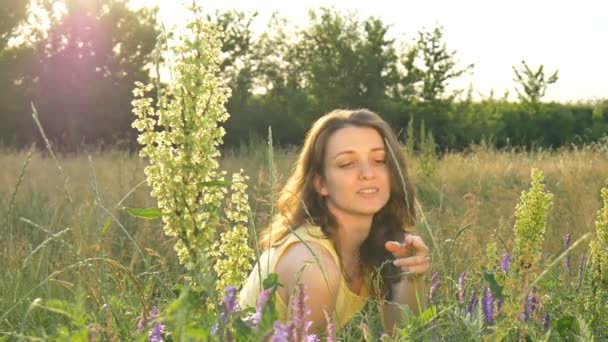 Gadis cantik sedang duduk di tengah lapangan dengan bunga selama musim panas, hipersensitivitas, asma, atau alergi konsep — Stok Video