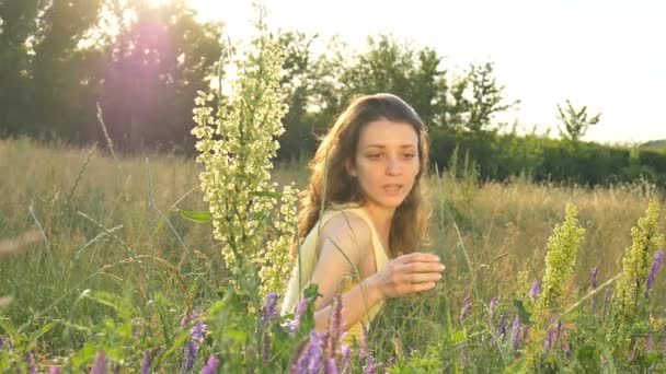 Ładna młoda dziewczyna siedzi na środku pola z kwiatami w okresie letnim, nadwrażliwość, astma, lub koncepcji alergii — Wideo stockowe