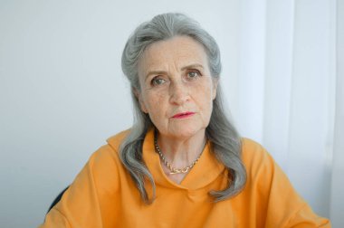 Gri saçlı, yüzü kırışık güzel yaşlı büyükannenin portresi kameraya bakıyor, anneler günü, mutlu emeklilik.