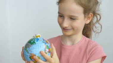Ukrayna Kiril alfabesiyle yazılmış ve içinde çiçekler büyüyen coğrafi isimlere sahip dünya küresi küçük sarışın bir kız tarafından tutuluyor. İnsan sorumluluğu, dünya ellerde, çevre dostu kavramlar