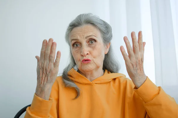 Κοντινό πορτραίτο θυμωμένης ώριμης ηλικιωμένης γυναίκας που μιλάει με κάποιον και κοιτάζει την κάμερα. Αρνητικό συναίσθημα, έκφραση προσώπου, σκάνδαλο. — Φωτογραφία Αρχείου