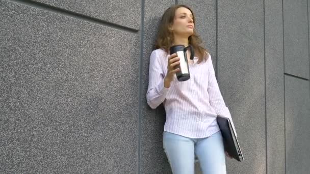 Retrato feminino de mulher jovem com laptop de prata e xícara de café esperando por uma reunião perto de parede cinza escuro na parte da manhã, trabalho remoto, coffeebreak, conceito de estudante inteligente — Vídeo de Stock