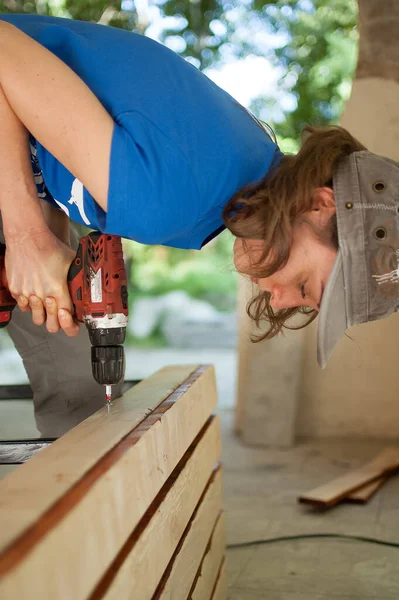 Abilità giovane operaia sta usando cacciavite di potenza di perforazione durante la costruzione banco di legno uguaglianza di genere, femminismo, fai da te concetti. — Foto Stock