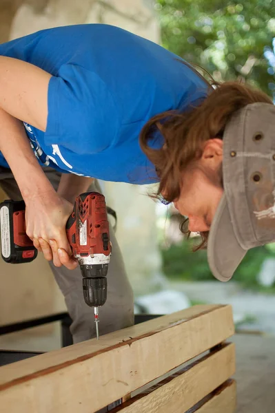 Abilità giovane operaia sta usando cacciavite di potenza di perforazione durante la costruzione banco di legno uguaglianza di genere, femminismo, fai da te concetti. — Foto Stock