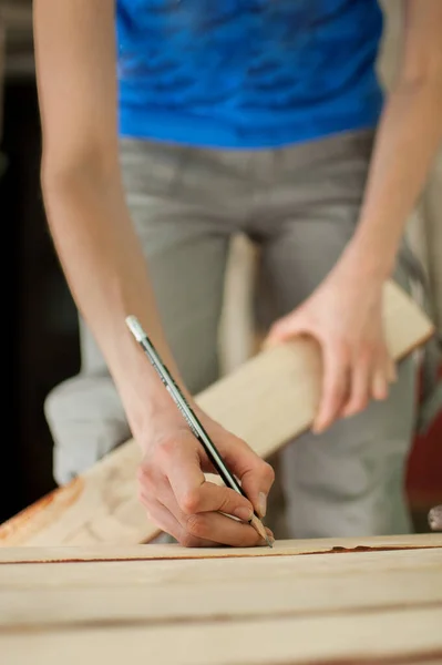 Ženské ruce dělají nějaké značky na dřevěném prkně pro budoucí otvory pomocí tužky pro montáž lavice, rovnost pohlaví, feminismus, udělej si to sám. — Stock fotografie