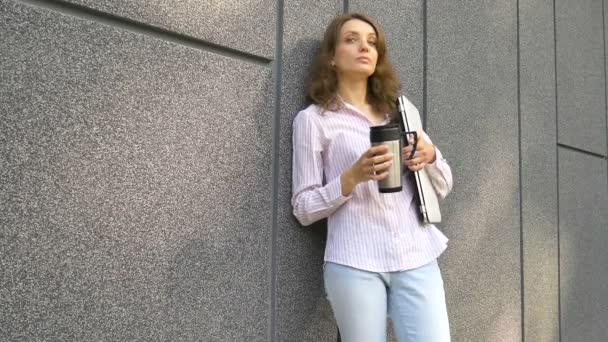 Portrait féminin de jeune femme avec ordinateur portable en argent et tasse de café en attente d'une réunion près du mur gris foncé le matin, travail à distance, pause café, concept étudiant intelligent — Video