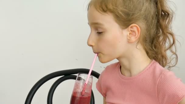 Dulce niña bebe batido de frambuesa y sonríe. Bebida vegetariana. Retrato de cerca de un niño que disfruta de un refrescante jugo de frambuesa sabroso, alimentación saludable — Vídeos de Stock