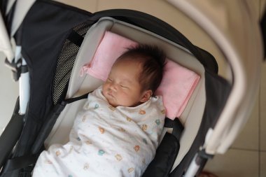 Asyalı Çinli bebek arabası içinde huzur içinde uyuyor