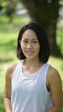 Asyalı Çinli bir kadın bahçede tatlı tatlı gülümsüyor.