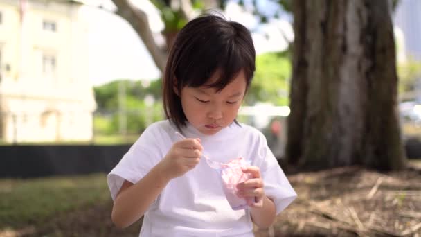アジア系中国人の女の子は初めてアイスクリームを空腹に食べる — ストック動画
