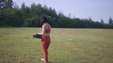 Yavaş hareket eden Asyalı Çinli kadın yoga minderini sabah güneşine koyuyor.