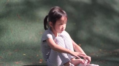 Yenilmiş Asyalı Çinli çocuk ayakkabısını çıkarıp çakıl taşlarını sallıyor.