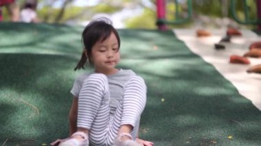 Yenilmiş Asyalı Çinli çocuk ayakkabısını çıkarıp çakıl taşlarını sallıyor.