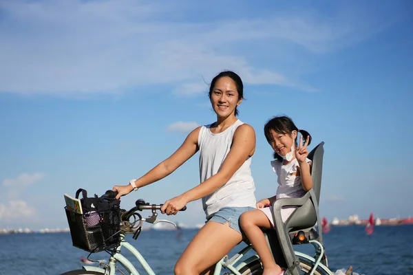 아시아계 어머니와 Covid 마스크 자전거타기 로열티 프리 스톡 이미지
