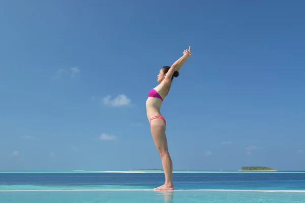 Asiatisk kinesisk kvinne som øver på yoga ved havet – stockfoto