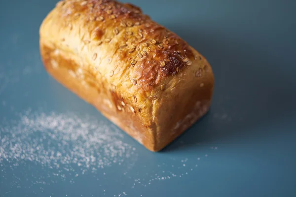 A loaf of fresh bread lying on colored surface — Stock Photo, Image