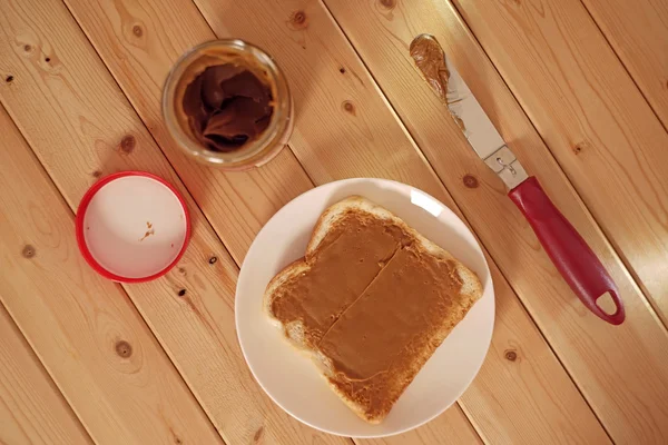 Spreading delicious peanut butter on white bread — Stock Photo, Image