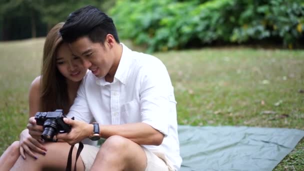 Asiatisches Paar beim Picknick im Freien beim Betrachten seiner eigenen Selfies — Stockvideo