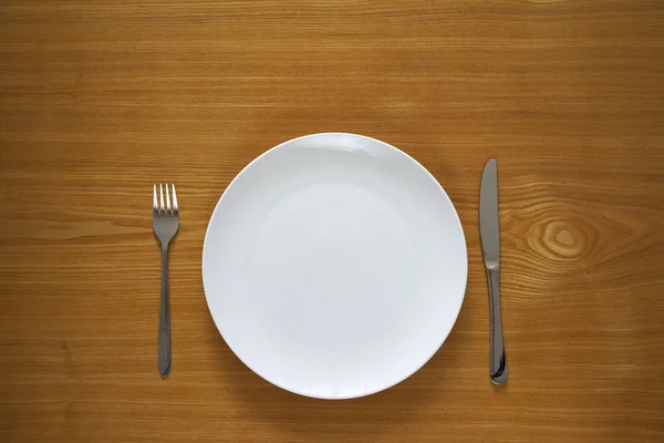 Empty porcelain plate on a wooden table top — Stock Photo, Image