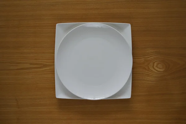 Empty porcelain plate on a wooden table top — Stock Photo, Image