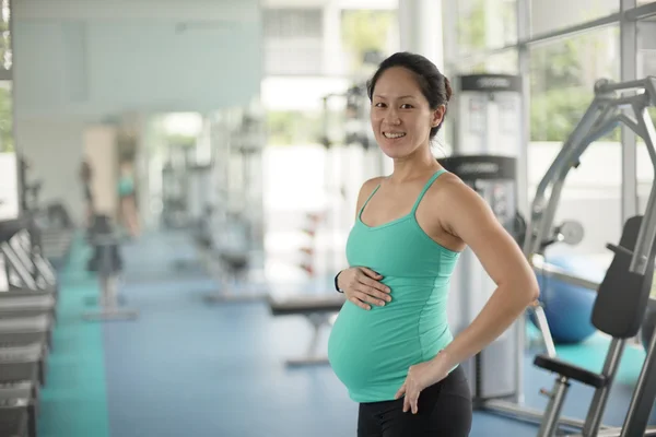 Kobieta w ciąży azjatyckich w siłowni utrzymując pasuje — Zdjęcie stockowe