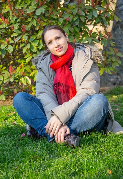 Woman sitting on the grass in red scarf Royalty Free Stock Images