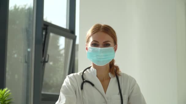 Junge kaukasische Ärztin entfernt medizinische Gesichtsmaske im Krankenhaus — Stockvideo