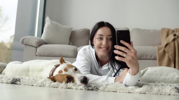 Jonge vrouw neemt een selfie met haar hond en gebruik telefoon in een prachtig modern appartement — Stockvideo