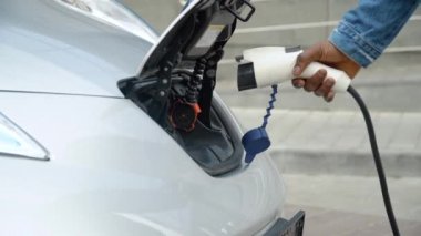 Siyah adamın elleri şarj olmak için elektrikli arabasını çalıştırıyor.