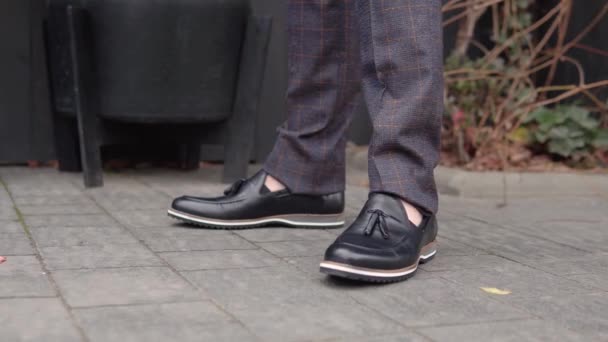 Крупним планом чоловічі ноги в коричневих штанях і нове чорне взуття з нової колекції — стокове відео
