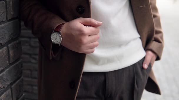 Primo piano di un bell'uomo d'affari in cappotto marrone con orologio su sfondo muro di mattoni — Video Stock