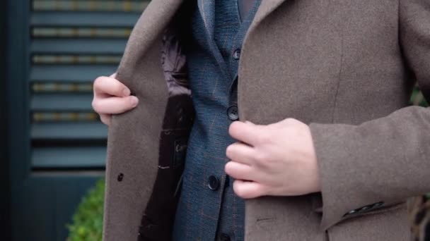 Ceketinin düğmelerini ilikleyen bir adamın yakın çekimi. Ofis merkezine yakın, kahverengi ceketli ve ceketli zarif bir erkek işadamı. — Stok video