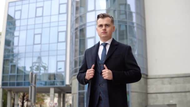 Joven y elegante hombre de negocios en chaqueta azul y abrigo cerca del centro de oficinas — Vídeo de stock