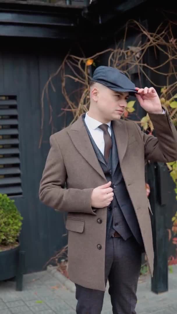 Portrait of a stylish businessman in brown coat on wooden background on street. Vertical video — Video