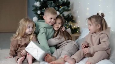 Noel ağacının yanında sarılan dört çocuk