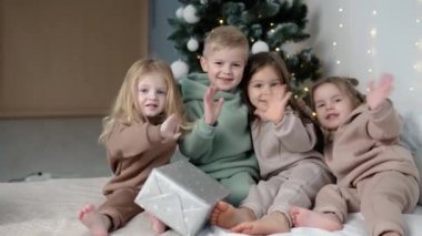 Çocuklar Noel ağacının yanında hoşça kal diyor. Çocuk konsepti için moda