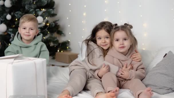 Kinderen knuffelen in de buurt van kerstboom — Stockvideo