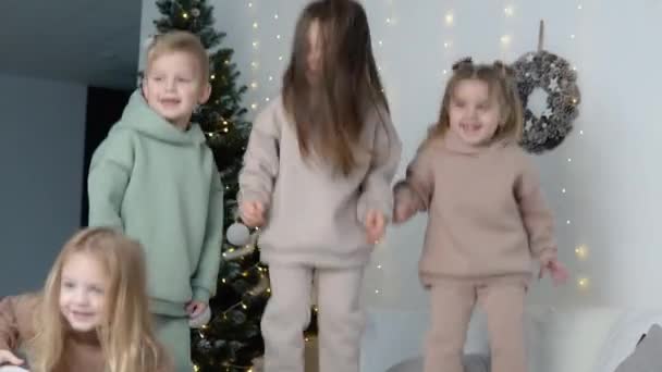 Niños saltando cerca de decoraciones navideñas — Vídeos de Stock