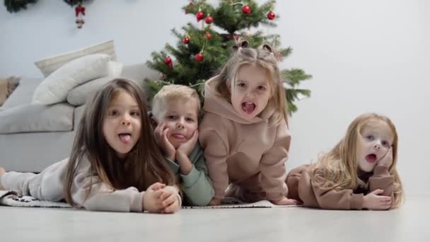Neşeli çocuklar Noel ağacının yanında yatıyordu. — Stok video