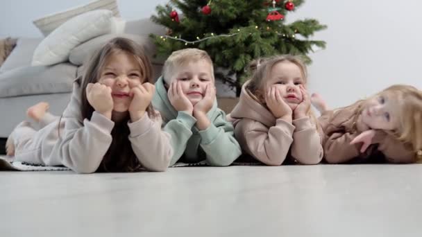 Neşeli çocuklar Noel ağacının yanında yatıyordu. — Stok video