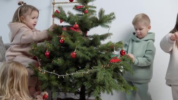 Şık takım elbiseli tatlı çocuklar Noel ağacını süslüyor. — Stok video