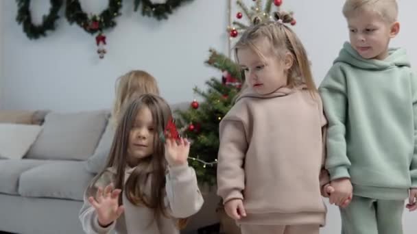 Dulces niños con elegantes trajes casuales decoran un árbol de Navidad — Vídeos de Stock