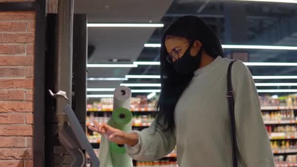 La fille dans un masque choisit des produits sur les étagères du supermarché. Concept commercial — Video