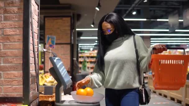 Dziewczyna w masce wybiera produkty na półkach w supermarkecie. Koncepcja zakupów — Wideo stockowe