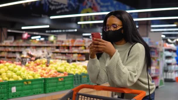 Gadis bertopeng berbicara di telepon di supermarket — Stok Video