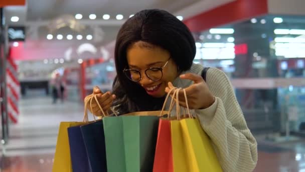 Dziewczyna entuzjastycznie patrzy w torby na zakupy — Wideo stockowe