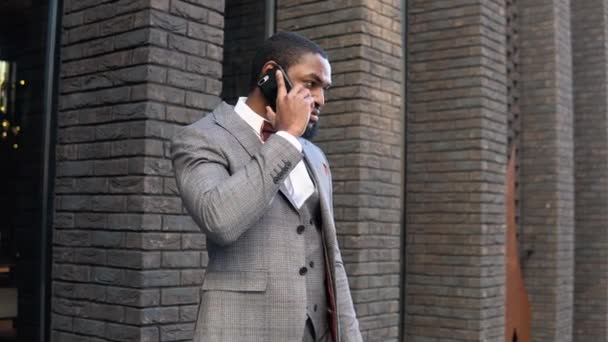 Молодой элегантный бизнесмен разговаривает по телефону возле офисного центра — стоковое видео