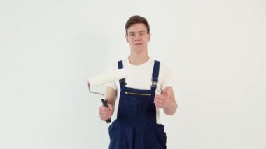 Elinde silindir olan bir ressam kameraya bakar.