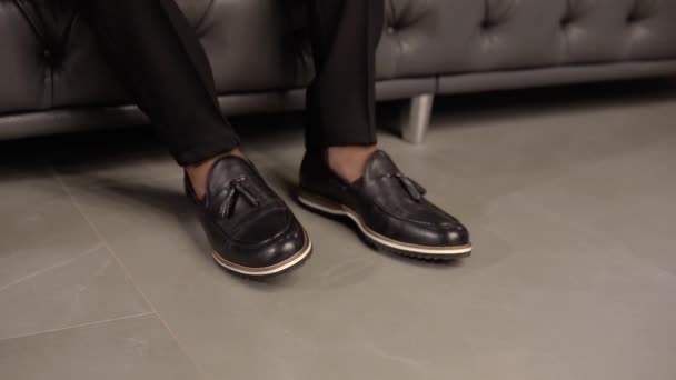 男がソファに座っているときにエレガントな男の靴を閉じます — ストック動画